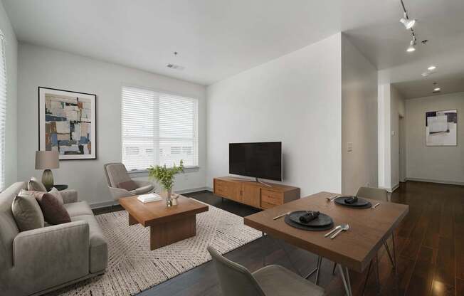 A modern living room with a grey couch, a wooden coffee table, and a television.