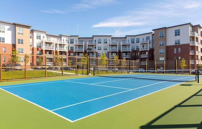 a tennis court with apartments in the background