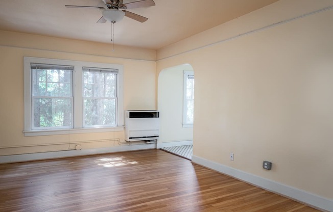 an empty room with hardwood floors and a ceiling fan