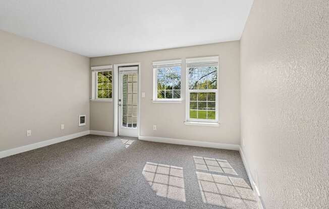 A room with a carpeted floor and a window showing a green lawn outside.