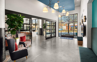 a lobby with chairs and a plant and glass doors