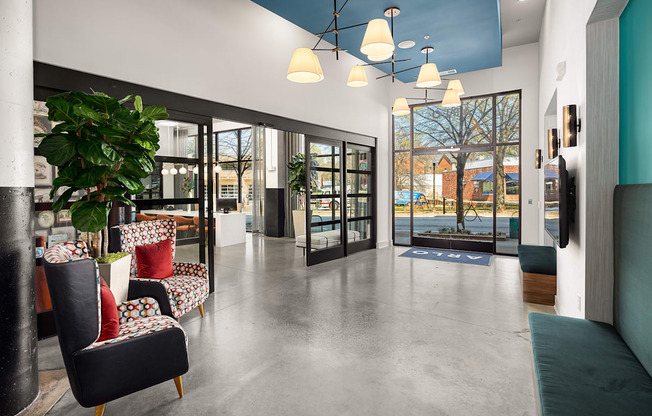 a lobby with chairs and a plant and glass doors