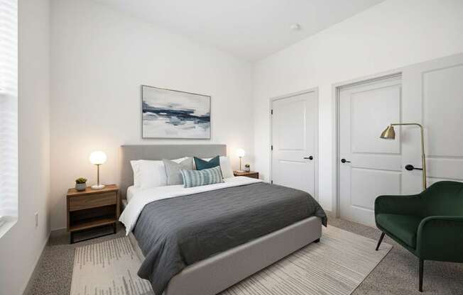 A bedroom with a large bed, a green chair, and a painting on the wall.