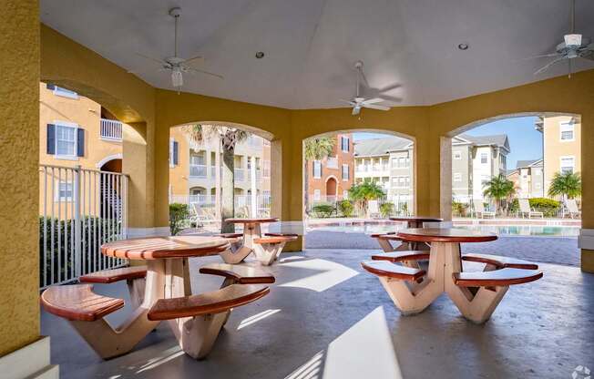 A patio with tables and chairs and a ceiling fan.