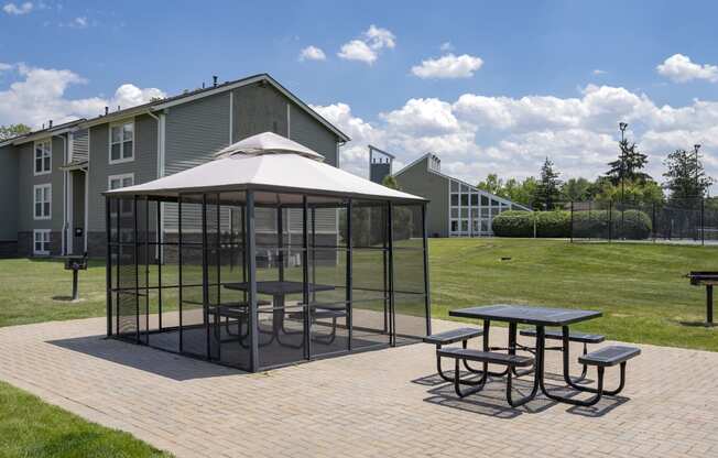 a gazebo with tables and chairs on a brick patio