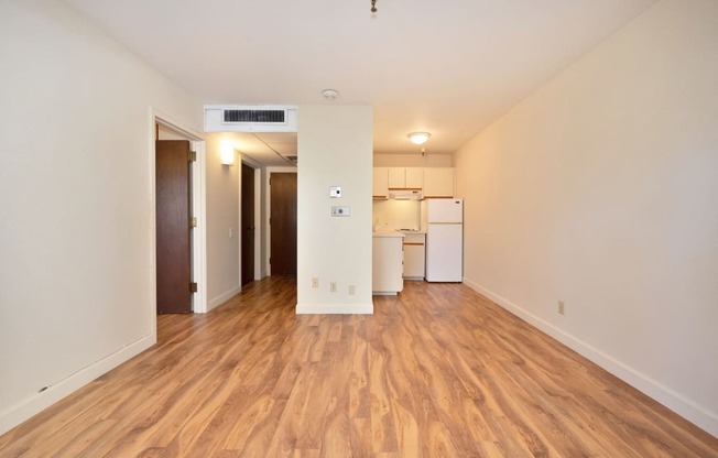 a living room and kitchen with wood flooring and white walls