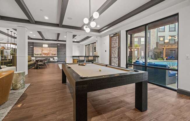 A billiard table is in the middle of a room with wood flooring.