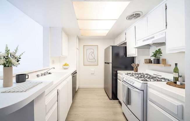 A modern kitchen with a black refrigerator and white cabinets.