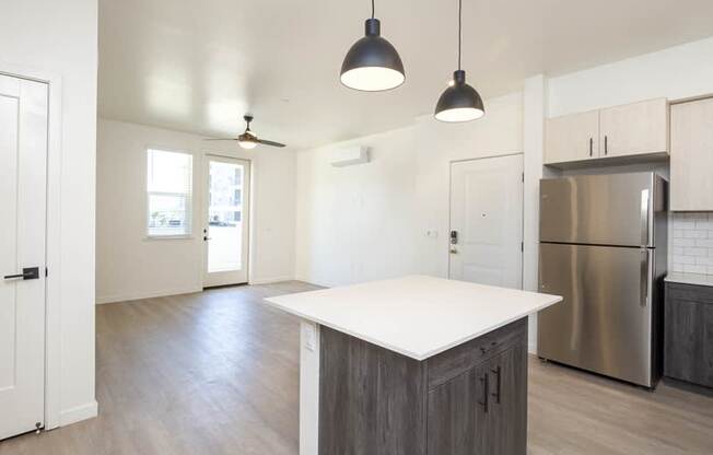 A kitchen with a white counter top and a stainless steel refrigerator.