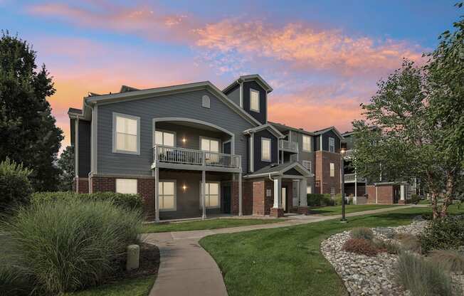 A modern two-story house with a balcony and a small garden in front.