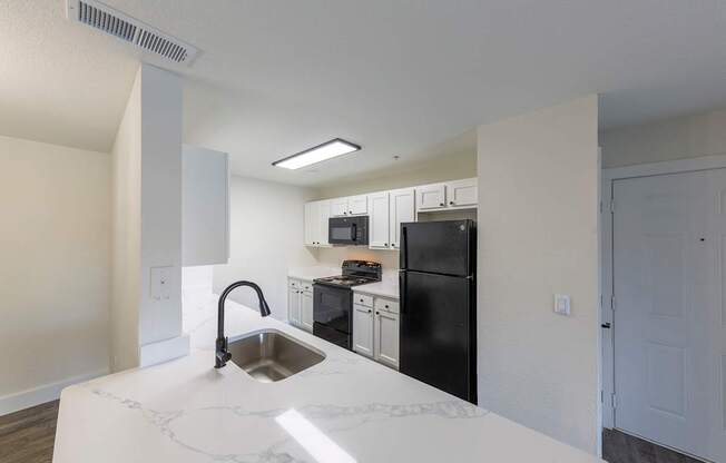 A kitchen with a sink and black appliances.