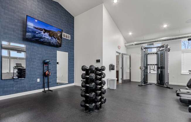 A gym with a television on the wall and various exercise equipment.