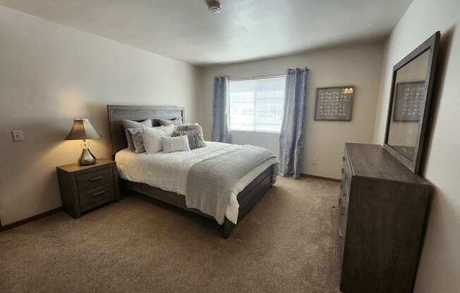 A bedroom with a large bed and a nightstand with a lamp.