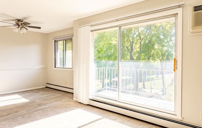 an empty living room with a large window and a balcony