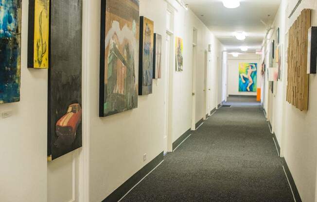 a hallway with paintings on the wall and a carpeted floor at MILEPOST 5 Apartments, PORTLAND Oregon