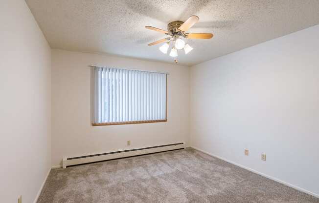 a bedroom with carpet and a ceiling fan. Fargo, ND Betty Ann Apartments