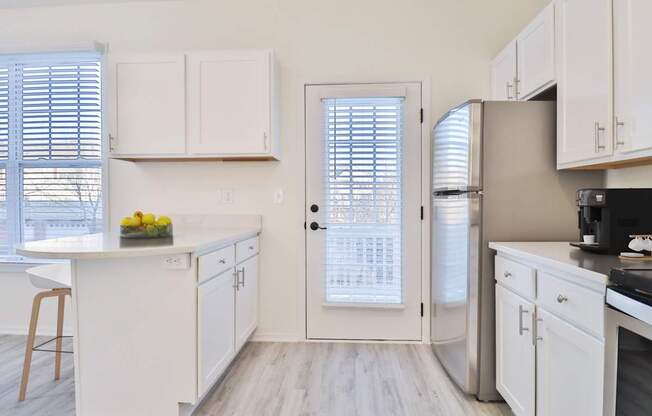 A kitchen with white cabinets and a refrigerator.