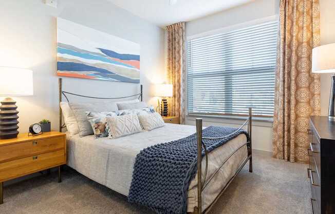 A bedroom with a large bed and a painting on the wall.