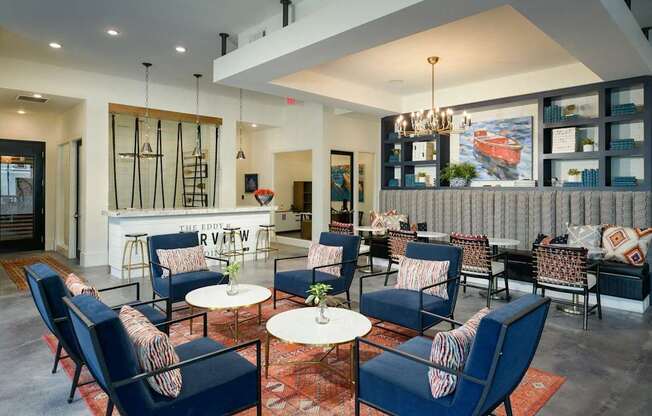 a lounge area with blue chairs and tables and a bar