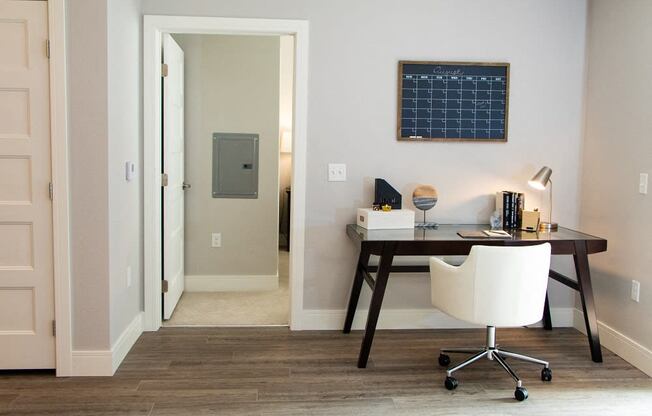 A white chair is in front of a desk with a black frame.