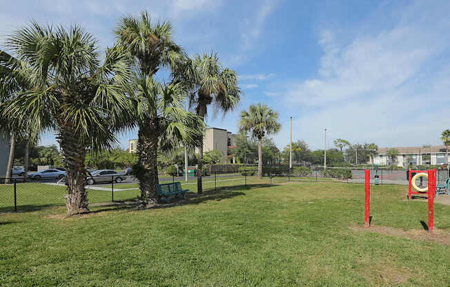 A park with a red pole and a green bench.