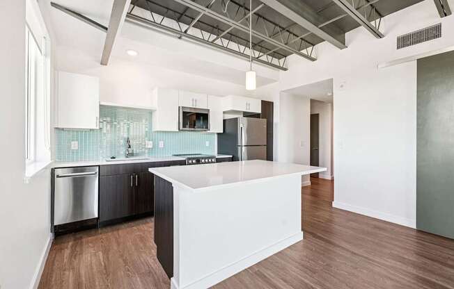 A modern kitchen with a white island and wooden floors.