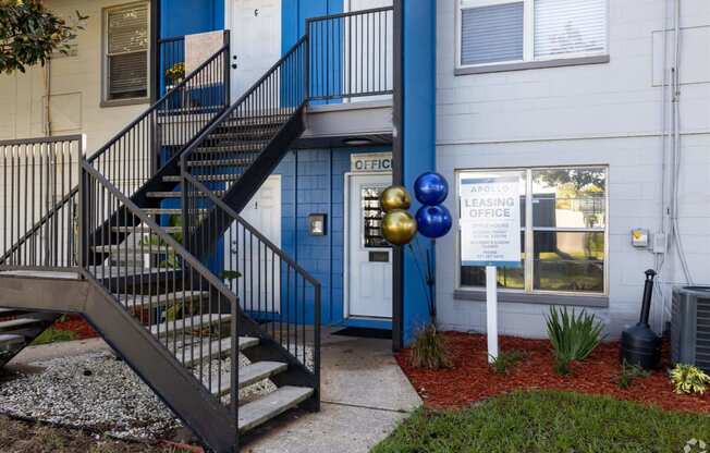 the front of a building with stairs and a sign in front of it