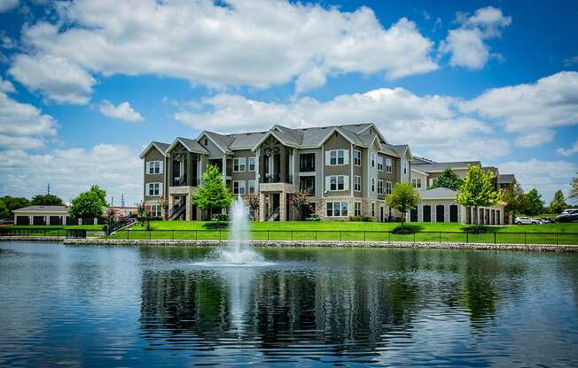a fountain in the middle of a lake with a large building in the background