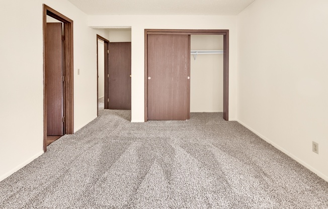 A room with a carpeted floor and three doors.