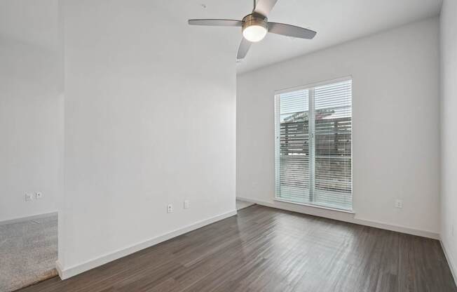 A room with a ceiling fan and a window with blinds.