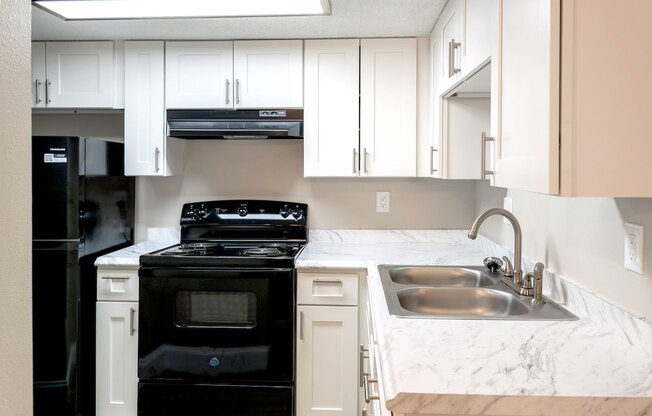 a kitchen with white cabinets and black appliances and a sink