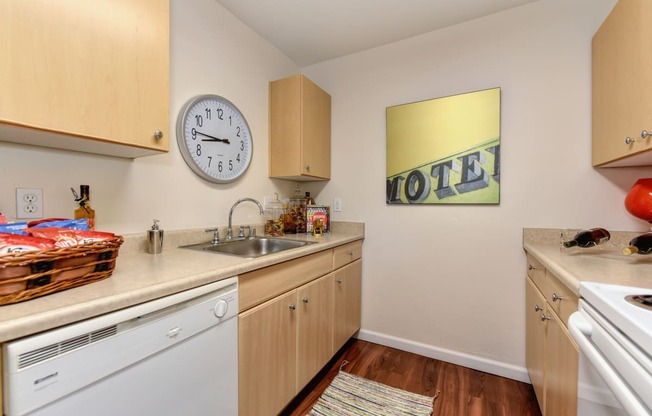 Model home kitchen with hardwood inspired flooring, white kitchen appliances, and cabinetry. 