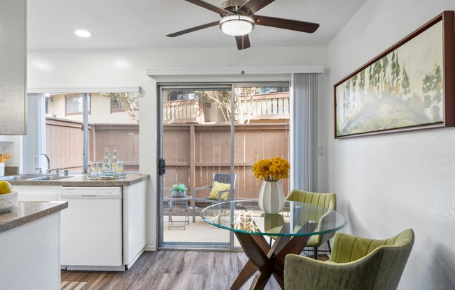 a kitchen and dining area with a glass table and chairs and a sliding glass door