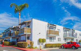 a car parked in front of an apartment building with a palm tree