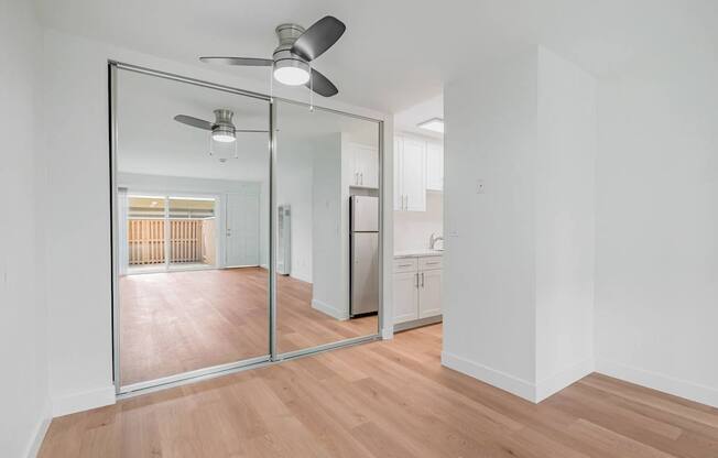 A room with a ceiling fan and a mirrored wall.