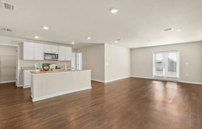 the living room and kitchen of a new home with wood flooring and white cabinets