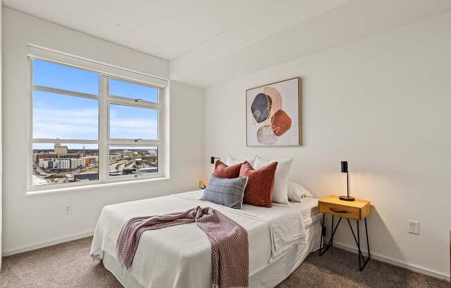 A bedroom with a large bed and a view of the city through the window.