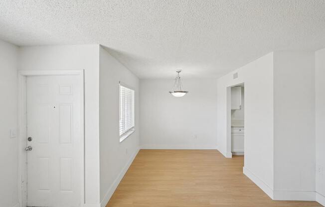 A white room with a door, a window, and a hanging light fixture.