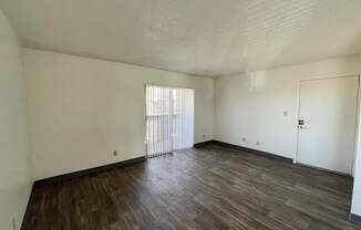A room with wooden flooring and white walls.