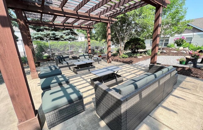 a covered patio with wicker furniture and a wooden pergola