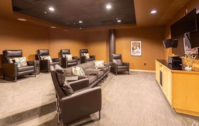 A theater room with brown leather chairs.