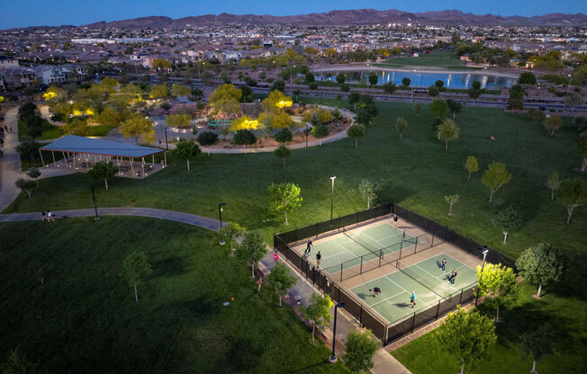 an aerial view of a tennis court with a city in the background