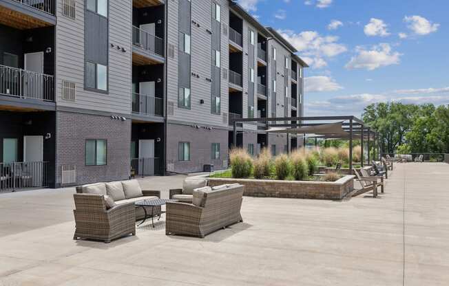 an outdoor patio with couches and chairs in front of a building