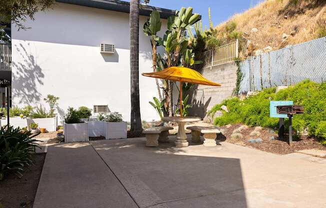 A patio area with a yellow umbrella and a white building in the background.