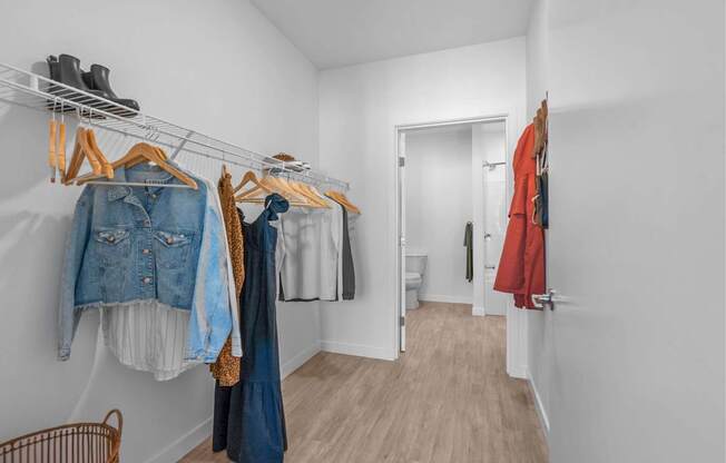 A hallway with clothes hanging on a rail and a door at the end.