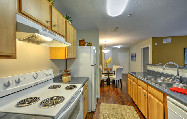 A kitchen with a stove, refrigerator, and sink.