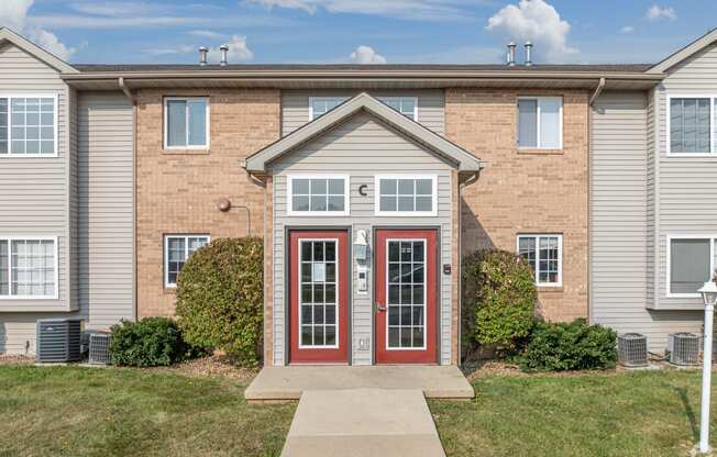 a brick apartment building with red doors and a sidewalk