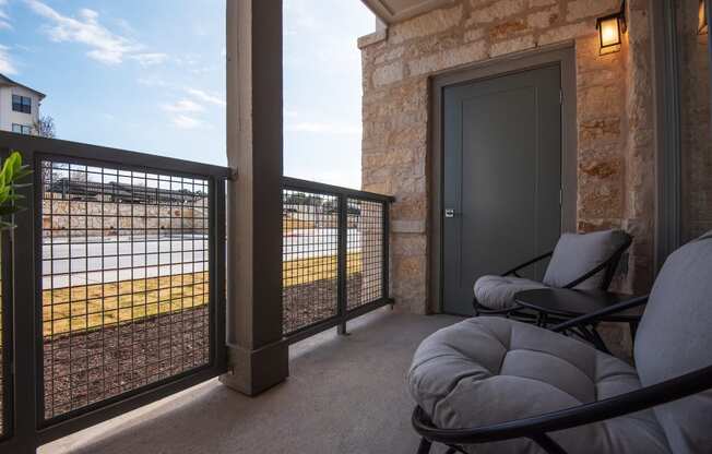 a covered porch with chairs and a door overlooking a body of water