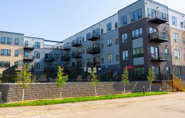 a view from the street of a large apartment complex with a brick wall in front of it