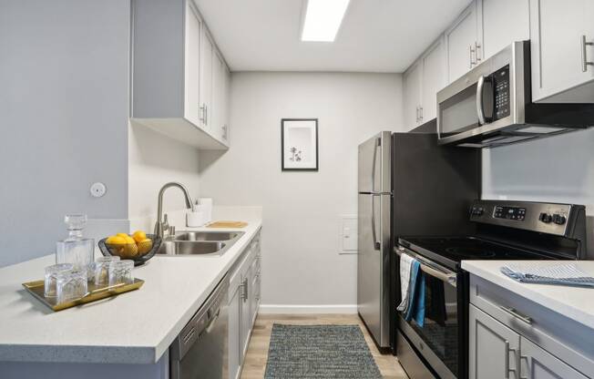 an apartment kitchen with stainless steel appliances and white cabinets